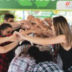 Group of diverse students engaging in a fun hand-holding activity indoors, symbolizing friendship and togetherness.
