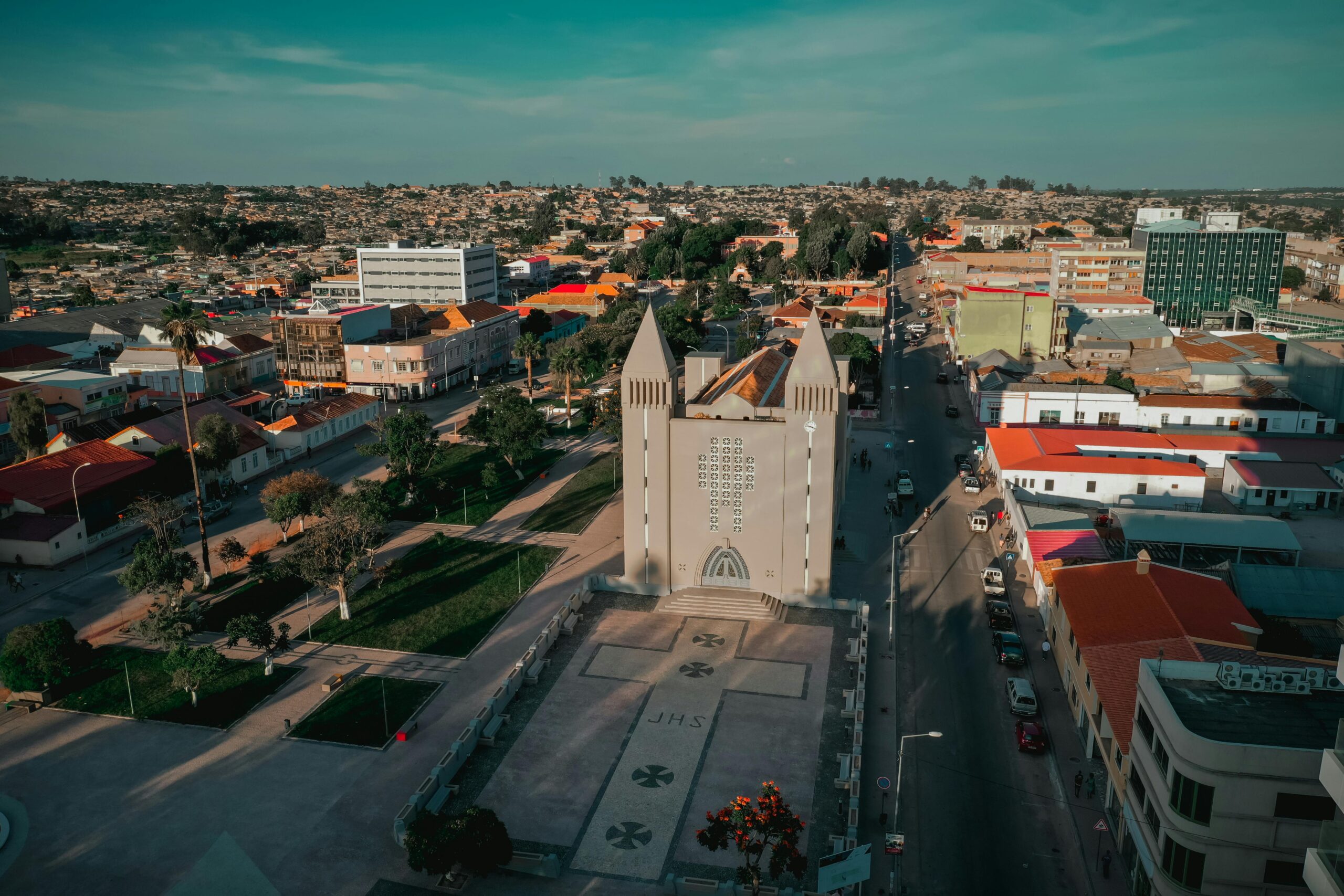 Aerial view of Lubango city with a prominent church in Huíla, Angola under a vibrant blue sky.